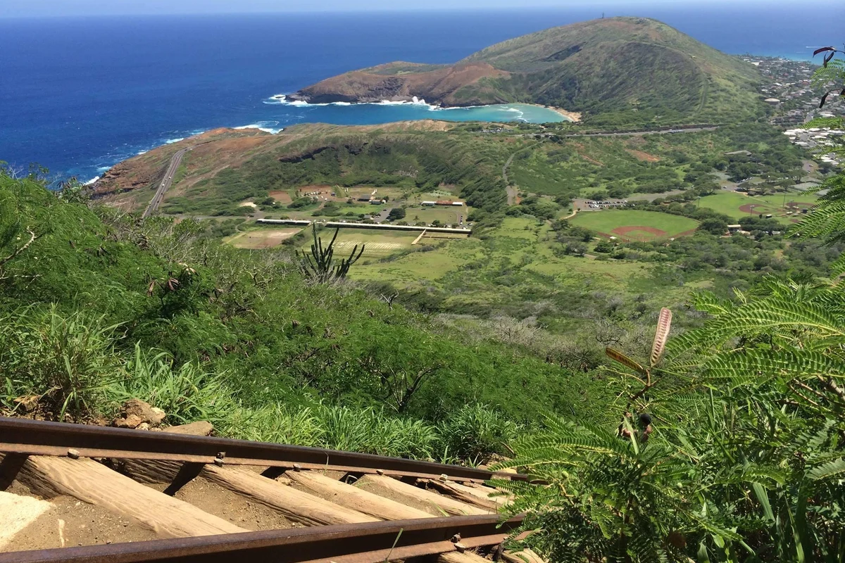 Hikers climbing the steep wooden railway stairs at Koko Crater, Oahu Hawaii toward the summit at sunset