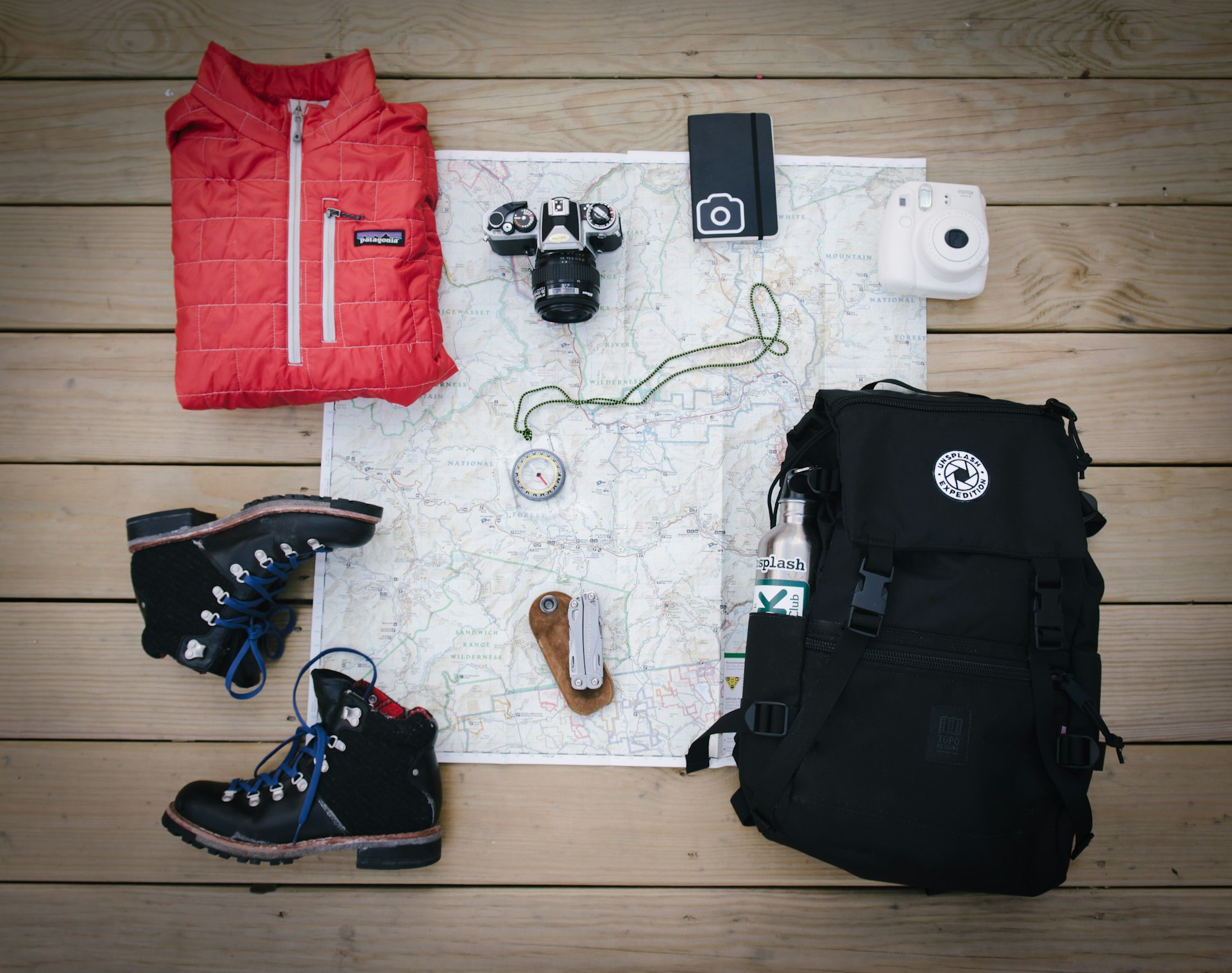 Hiking backpack, boots, map and camera laid out as a packing checklist for a volcano tour